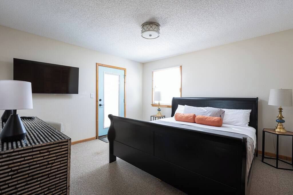 A bedroom with a black bed, white bedding, and two bedside lamps.