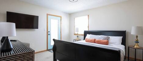 A bedroom with a black bed, white bedding, and two bedside lamps.