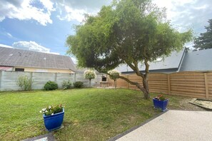 Enjoy a serene outdoor space with a well-manicured lawn, a large tree, and a patio area.
