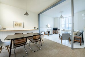 Un salon moderne comprenant un coin repas, une cheminée et une grande fenêtre laissant entrer la lumière naturelle.