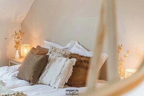 Ein ordentlich bezogenes Bett mit mehreren Kissen und einer Nachttischlampe.