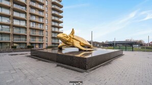 Una estatua dorada de una figura a caballo frente a un edificio moderno.