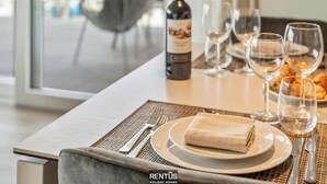 Une table à manger dressée avec une bouteille de vin, des verres, des assiettes et des couverts.