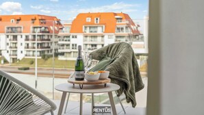 Un balcon avec une table dressée pour deux personnes, une bouteille de champagne et des plats remplis de nourriture.