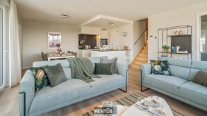 Un salon moderne avec deux canapés, un coin repas et une cuisine.