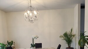 Un espace repas avec une table en marbre, des chaises noires et un lustre moderne.