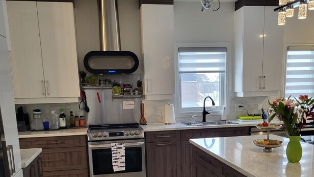 Une cuisine moderne dotée d’un îlot central, d’appareils électroménagers en acier inoxydable et de meubles de rangement en bois.