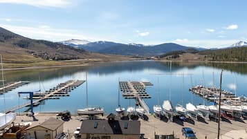 Un puerto deportivo con barcos amarrados, un edificio pequeño y una vista despejada de montañas al fondo.