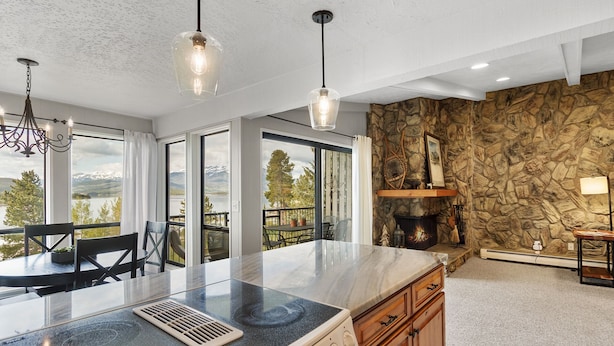 A modern kitchen with a large island, stone wall, and a fireplace.