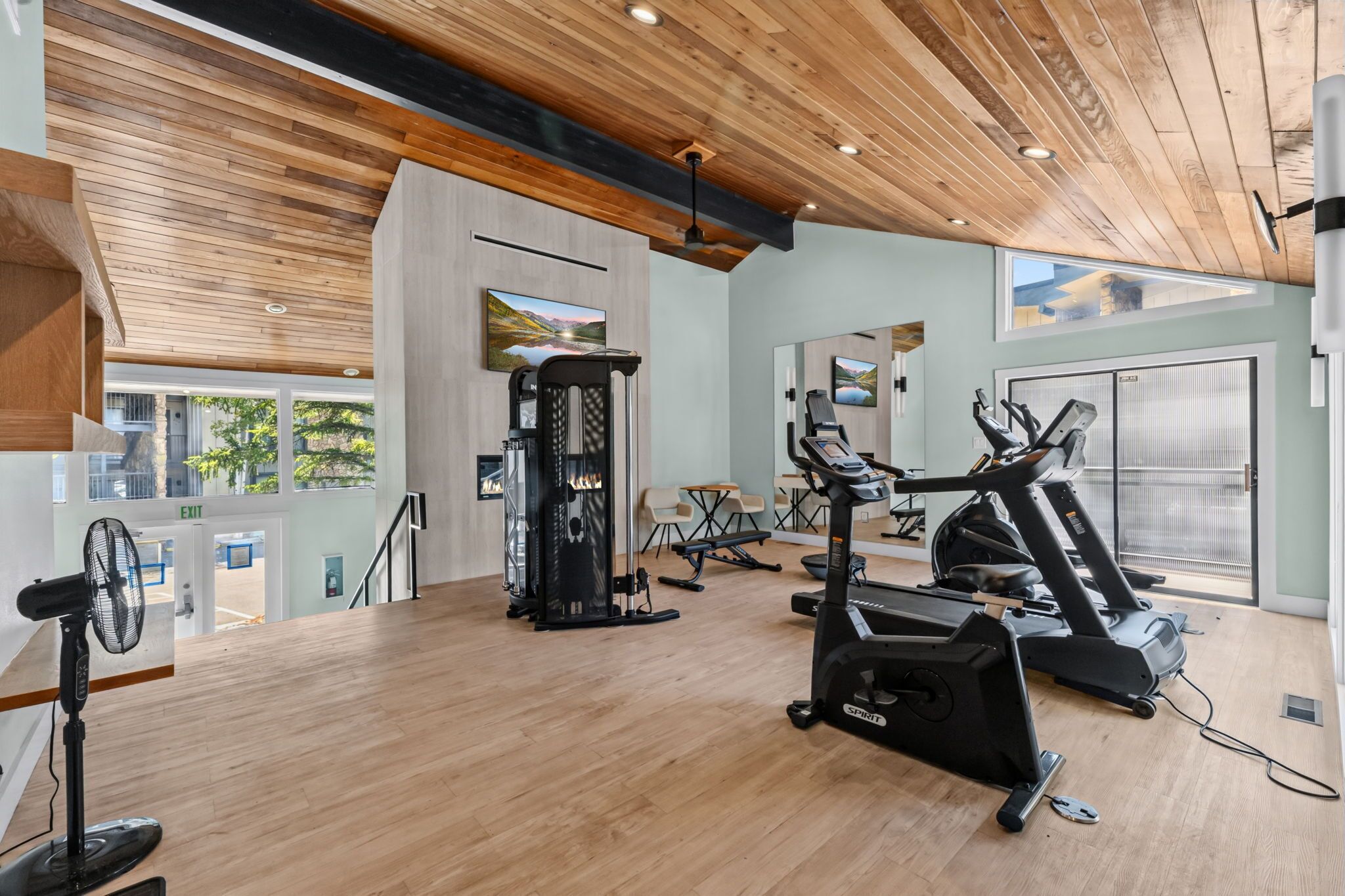 Un gimnasio con máquinas de cardio, una banca de pesas y un ventilador.