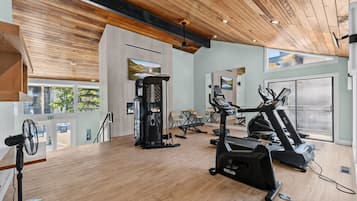 Un gimnasio con máquinas de cardio, una banca de pesas y un ventilador.