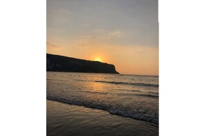 Enjoy breathtaking ocean views from a serene beach with gentle waves and dramatic cliff formations.