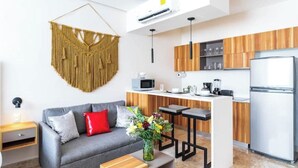 Una sala de estar moderna con un sofá gris, una mesita de madera y un tapiz decorativo de macramé.