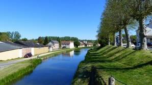 Ein Kanal mit Häusern an einer Seite und einer grasbewachsenen Uferböschung an der anderen.