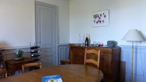 Ein Essbereich mit Holztisch, Stühlen, einem Schrank mit Weinflaschen und einer Lampe.