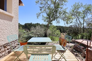 An outdoor patio with a table and chairs, surrounded by trees and a stone wall.