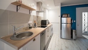 Une cuisine moderne dotée d’un évier en acier inoxydable, d’un plan de travail en bois, d’un four encastré et d’un réfrigérateur compact.