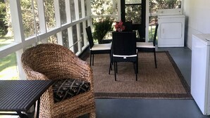 Un porche techado con muebles de mimbre, una mesa y sillas.