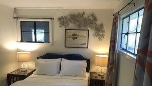 Un dormitorio con una cama, dos mesitas de noche, un ventanal y una obra de arte en la pared.