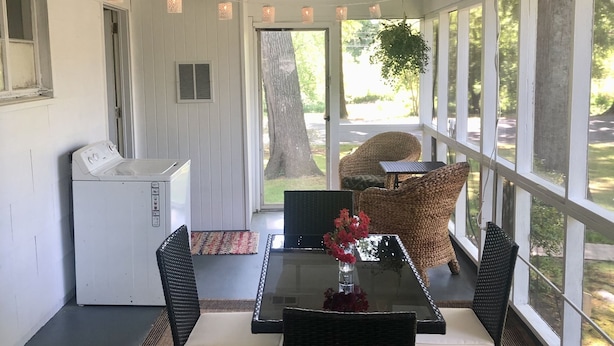 Un patio techado con mesa, sillas y un refrigerador.
