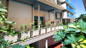 Un hôtel à plusieurs étages doté d’un espace extérieur couvert, de colonnes et de plantes en pot.