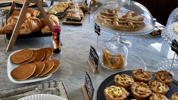 A buffet setup with various food items, including pastries, fruits, and beverages.