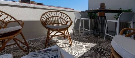 A terrace with wicker chairs, a table, and a newspaper.