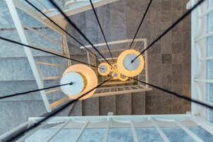 A modern interior with a spiral staircase and a ceiling with circular light fixtures.