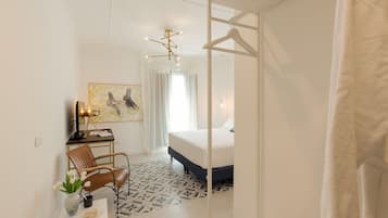 Un dormitorio moderno con una cama, un escritorio con una silla, una lámpara colgante y un cuadro en la pared.