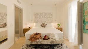 A hotel room with a large bed, a nightstand, a desk, and a chair.