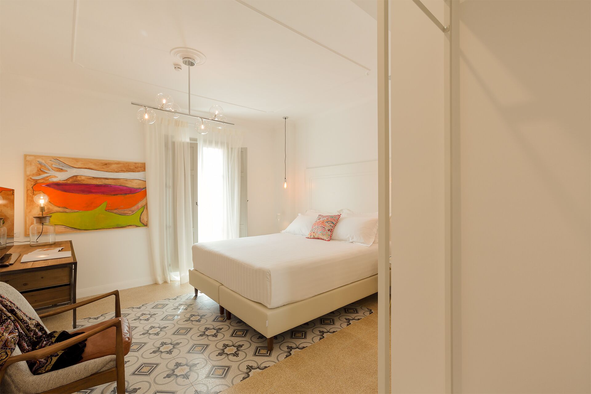 Ein Schlafzimmer mit einem Bett, einem Stuhl, einem Schreibtisch und einem Gemälde.