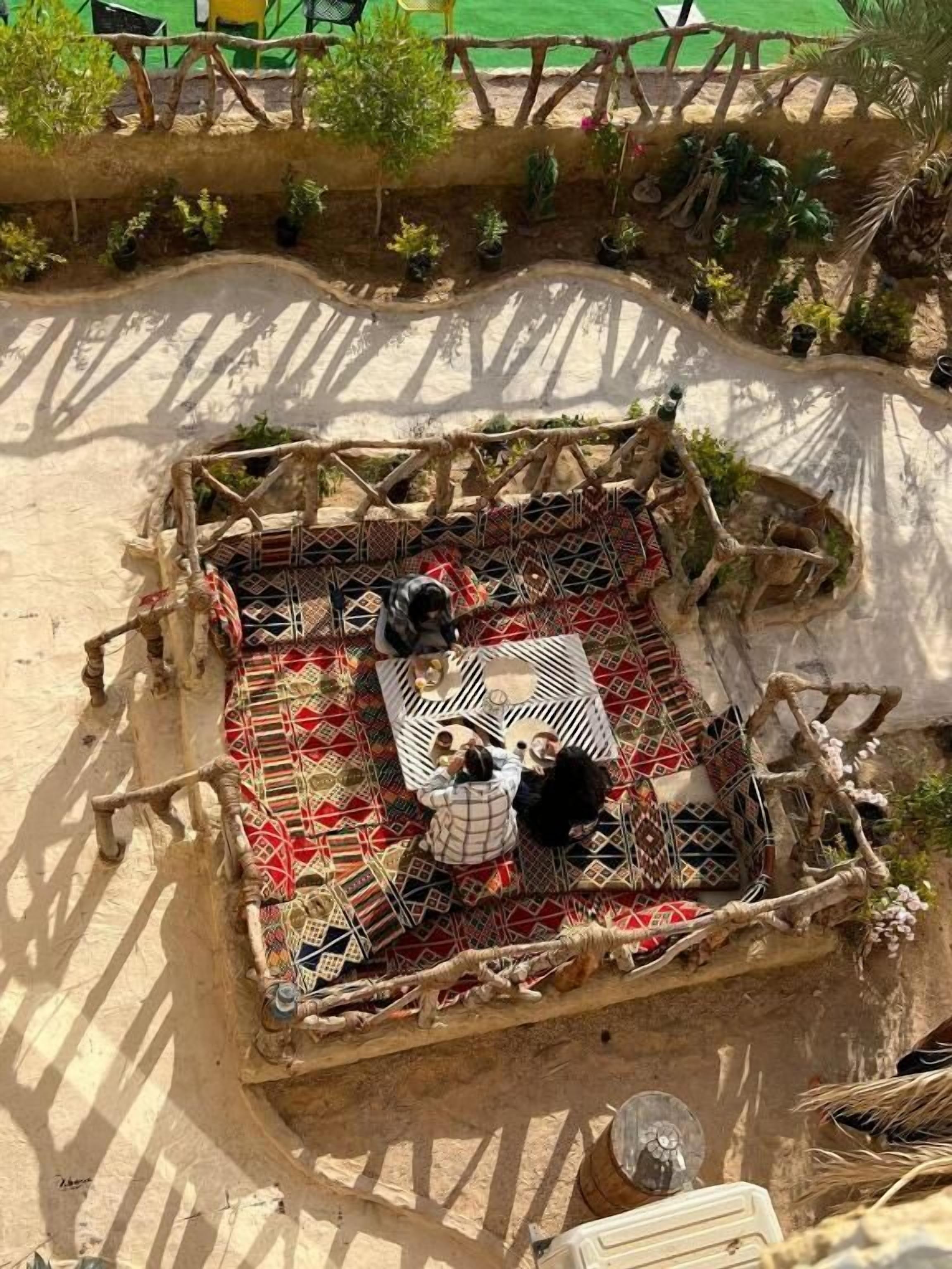 Un espacio de descanso al aire libre con suelo estampado, rodeado por una valla de madera rústica y pequeñas plantas.