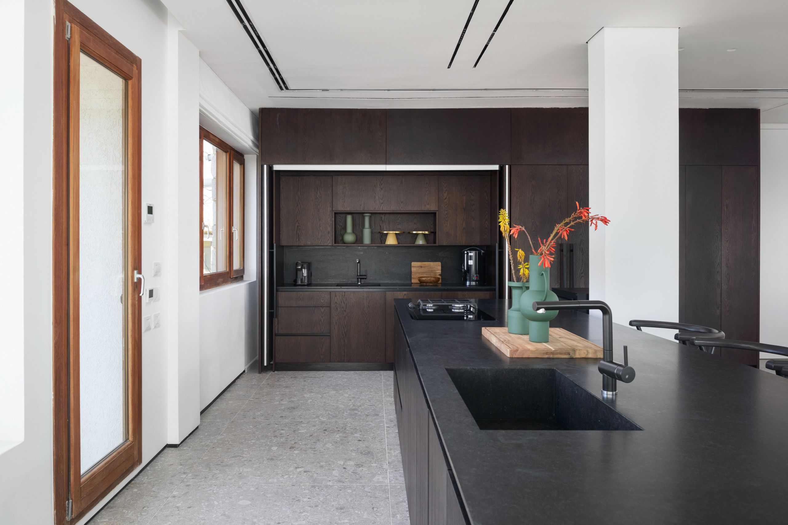 Een moderne keuken met donkerhouten kasten, een zwart aanrecht en een houten snijplank.