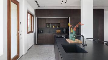 Een moderne keuken met donkerhouten kasten, een zwart aanrecht en een houten snijplank.