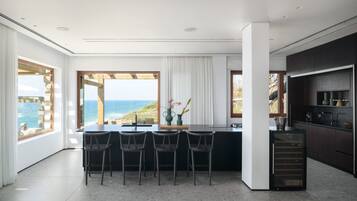 Una cocina moderna con una isla grande, taburetes de bar y vista al océano.