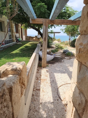A stone pathway leading to a wooden pergola with a view of the sea. - Luxury Villa over the Cliffs by FeelHome (Hefer Valley)