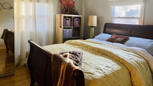 Un dormitorio con cama, mesita de noche, lámpara, armario y ventana con cortinas.