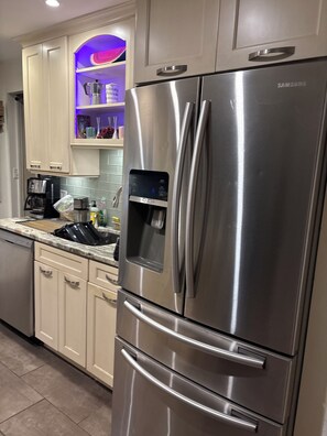 Un refrigerador Samsung de acero inoxidable con dispensador de agua, una cafetera y un microondas en la encimera.