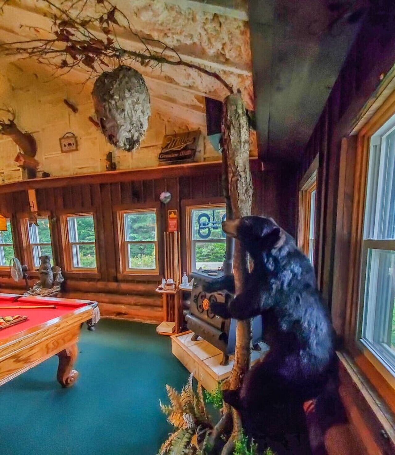 Un intérieur en bois agrémenté d’une table de billard, d’une statue d’ours et d’une décoration rustique.