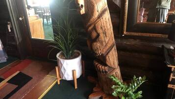 A wooden bear sculpture, a potted plant, and a mirror in a room with a patterned carpet.