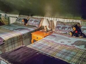 Una habitación con dos camas, una mesita de noche y una lámpara.