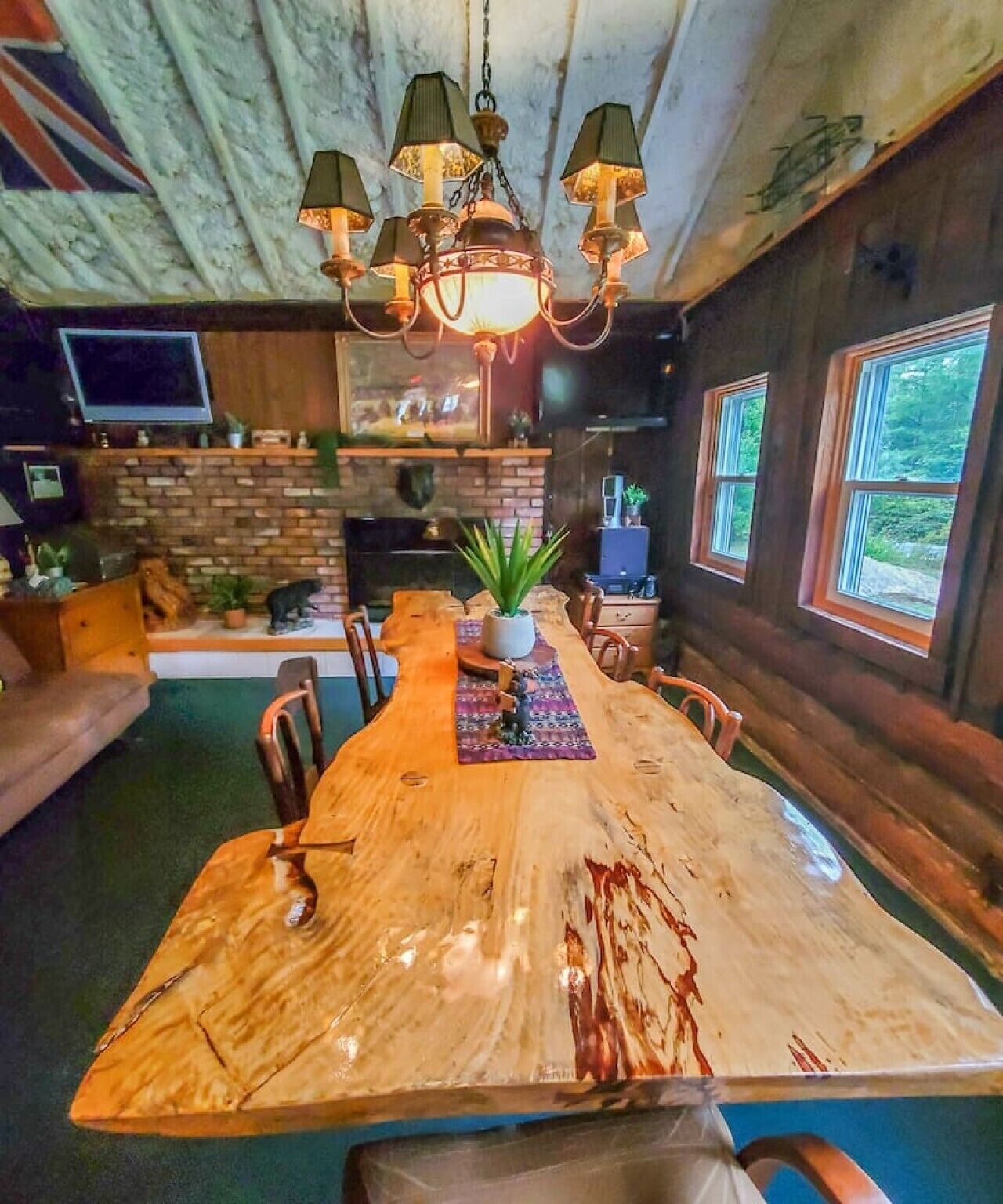 Une table à manger en bois rustique, avec des chaises, un lustre et un mur en briques.