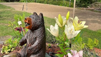 A garden with a bear statue, flowers, and a dirt path.