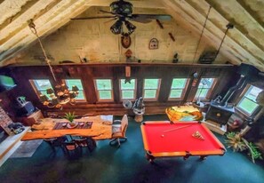 Una stanza accogliente con tavolo da biliardo, tavolo da pranzo in legno e ventilatore a soffitto.