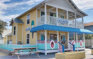 A creamery building with a blue awning, a covered porch, and a picnic table.