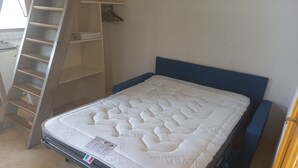 Een slaapkamer met een bed, een garderobe en een rek voor spullen.