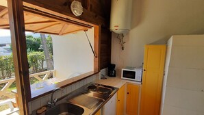 Een kleine keuken met een spoelbak, fornuis, magnetron en boiler.