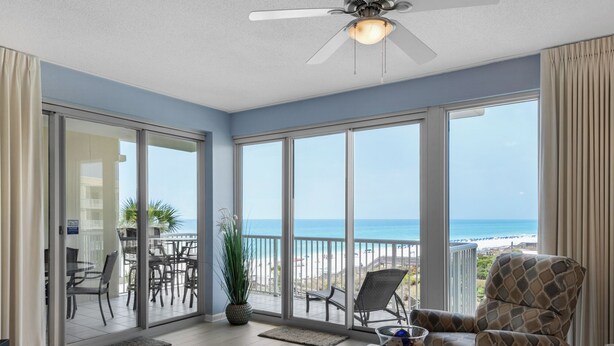 A spacious living room with a large glass door leading to a balcony overlooking a beach. - Beautiful Gulf Front 2 Bedroom Condo in Destin (Miramar Beach)