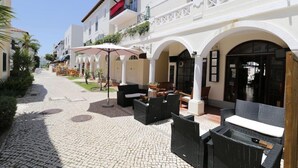 A courtyard with outdoor seating, a covered area, and a building with arches and balconies. - Old Village (Loulé)