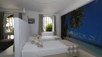 A bedroom with two beds, a large window, and a mural of a beach scene.
